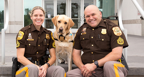 two police officers and a Canine Companions service dog