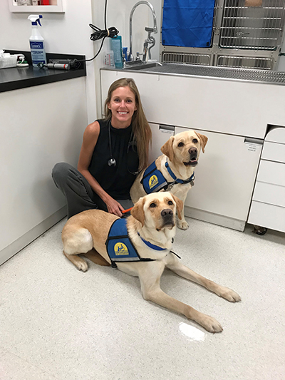 person sitting with two Canine Companions service dogs