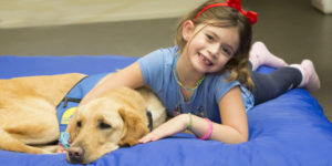 child lying down with Canine Companions service dog