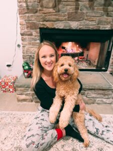 A woman sitting in front of a fireplace with a golden puppy
