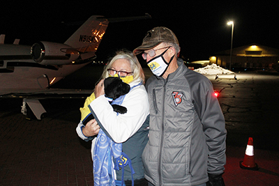 two people at airport holding Canine Companions puppy