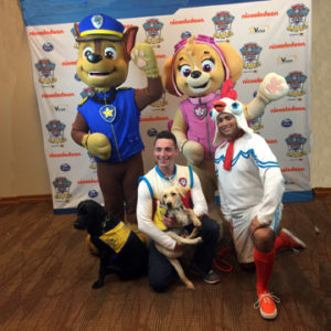 2 people and dogs stand with costumed Paw Patrol characters
