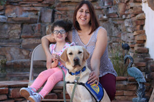 child and adult sitting with canine companions service dog