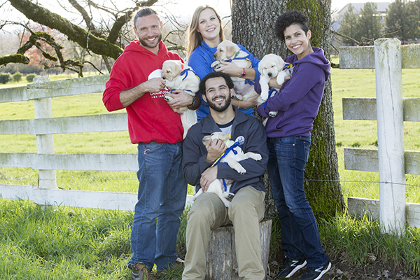 four people holding Canine Companions puppies