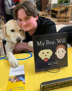 Adolescent with service dog at a table