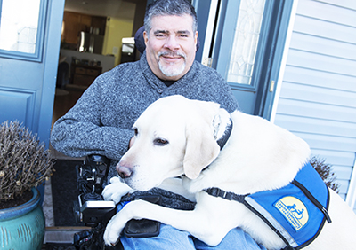 man sitting in chair with Canine Companions service dog