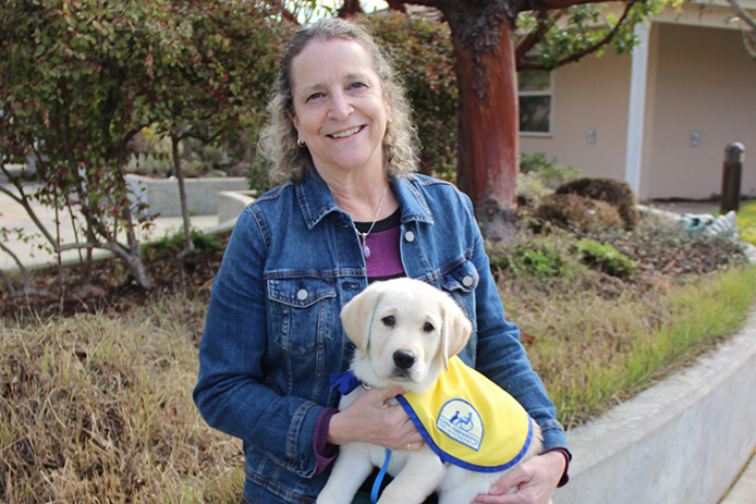 person sitting and holding a Canine Companions puppy