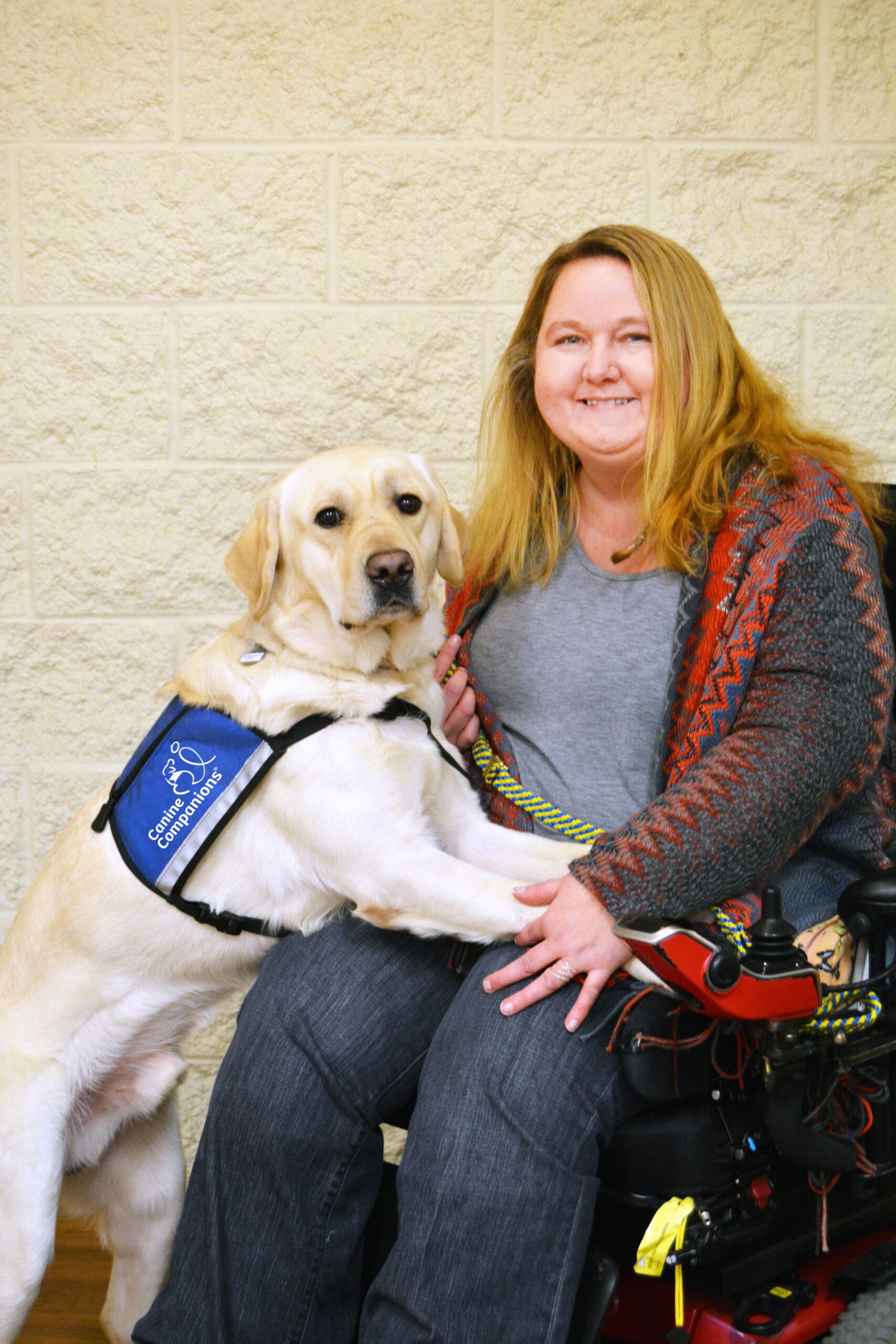 woman in wheelchair with Canine Companions service dog resting on her lap