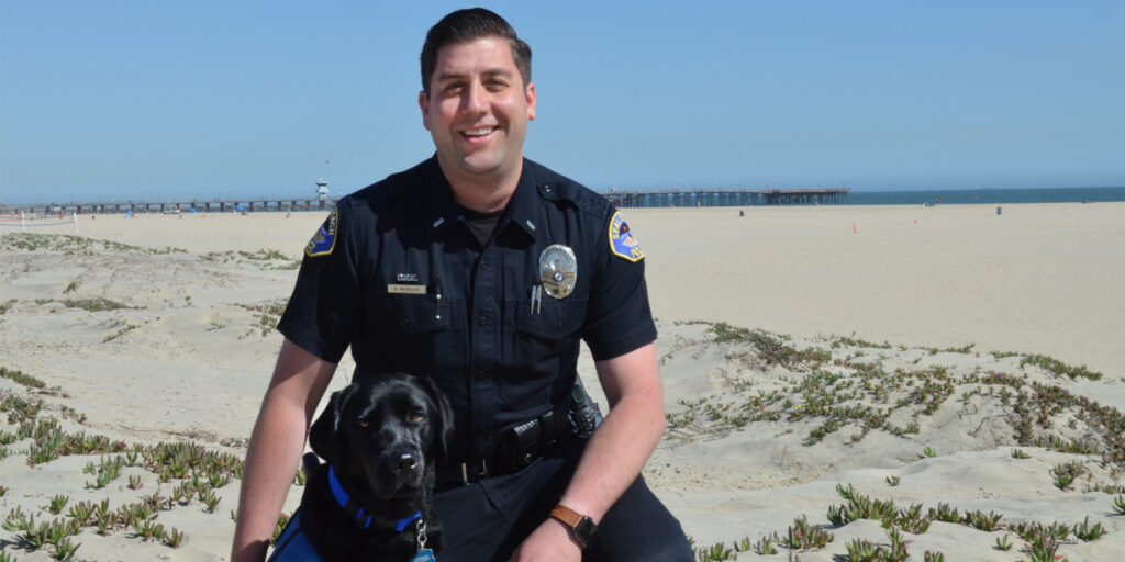 Officer with facility dog on the beach