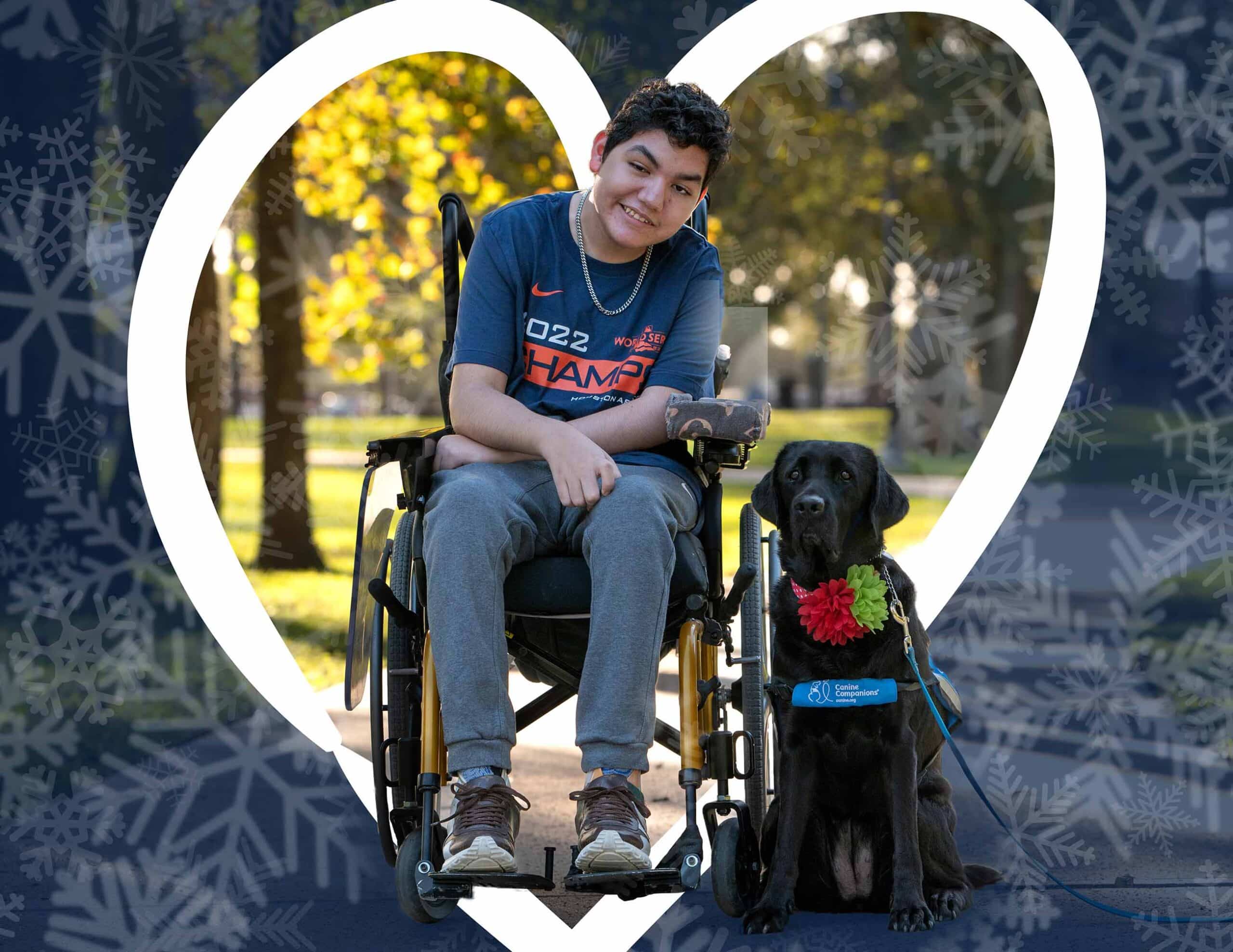 A smiling boy in a wheelchair next to a black lab service dog in a blue service vest.