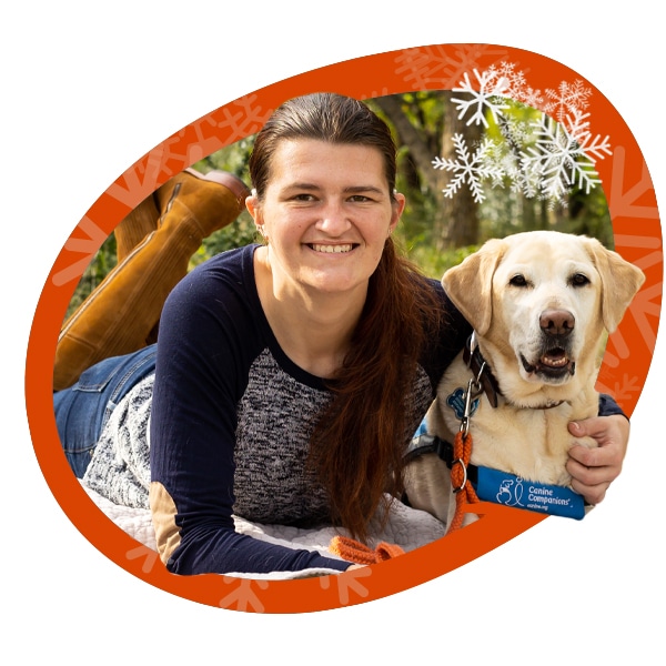 a circle with snowflakes around the image of a smiling girl laying on the grass next to a yellow lab service dog in a blue vest with an orange hearing dog leash