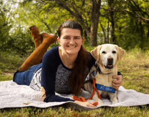 Young woman lying down on the grass with her hearing dog
