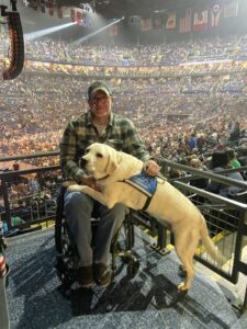 Veteran Jay and Service Dog Flurry post in front of a packed arena.