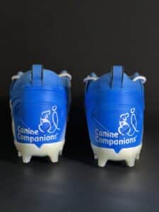 The Canine Companions logo is highlighted on the back of blue cleats.
