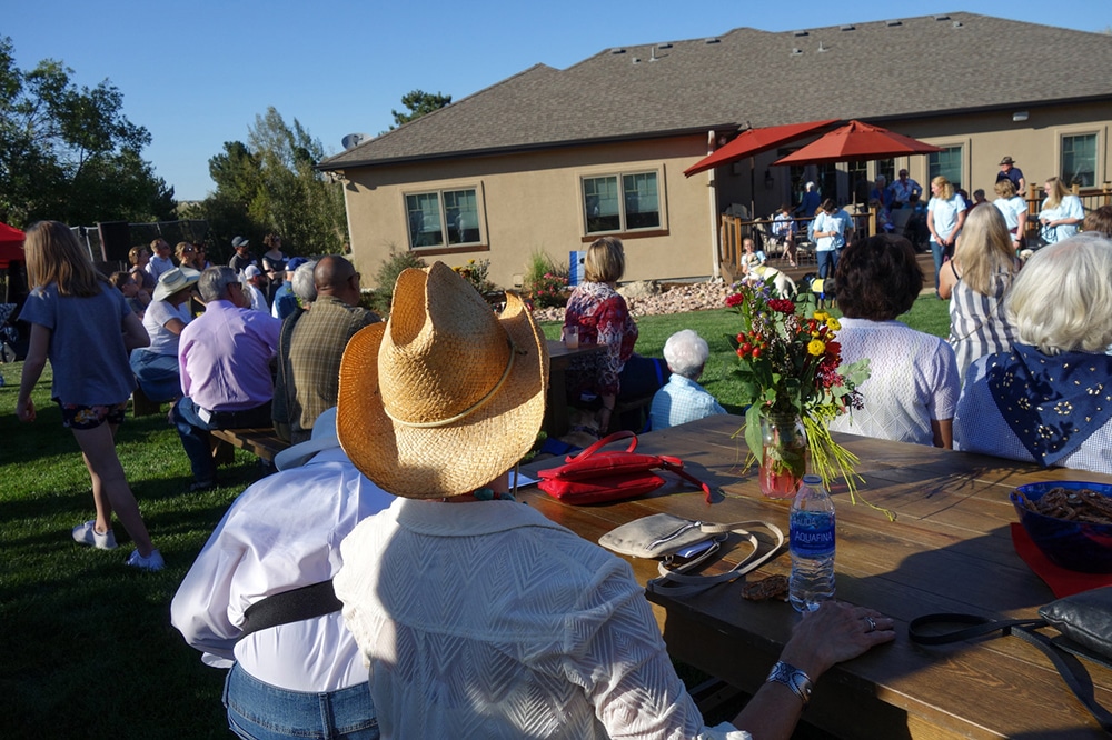 Group of people in the yard seating on tables