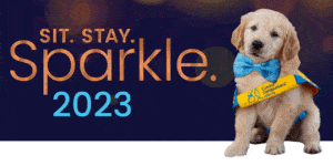 Golden Retriever puppy wearing a yellow vest and blue sparkly bowtie 