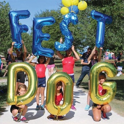seven children holding a letter balloon each, spelling out DogFest at a park