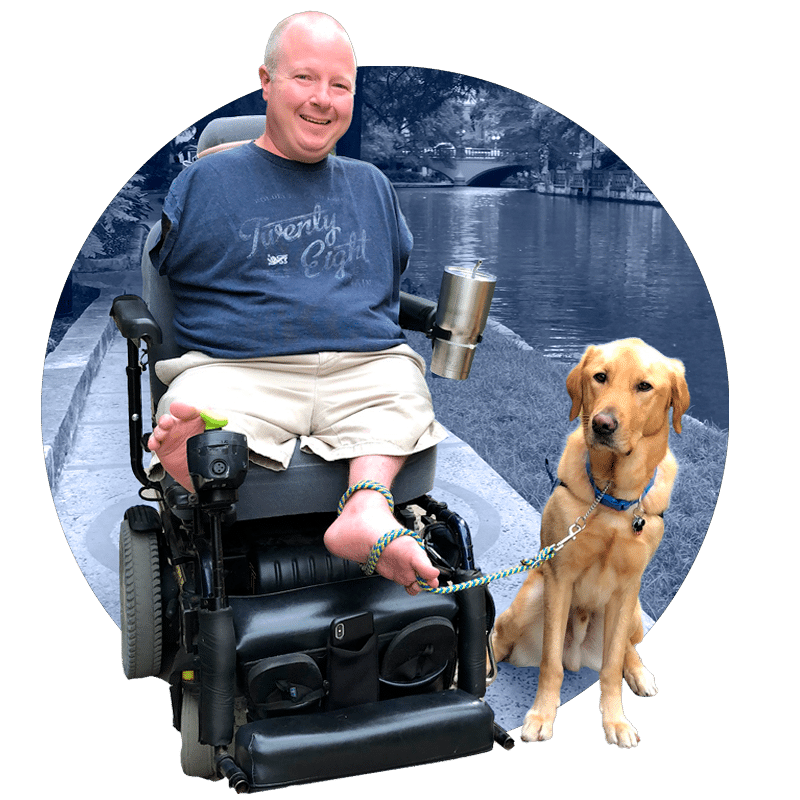 a man in a motorized wheelchair with a yellow lab service dog sitting beside him