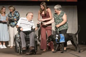 Volunteer puppy raisers handing service dog leash to new graduate