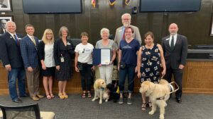 Photo with 10 adults, 2 puppies in training and one service dog receiving the colorado proclamation