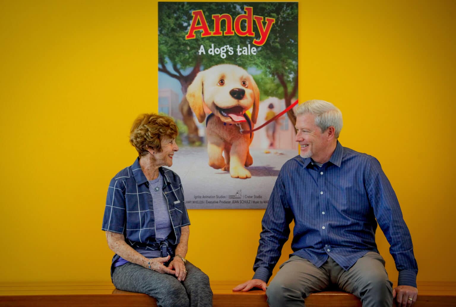 Man and woman seating with the Andy film poster behind