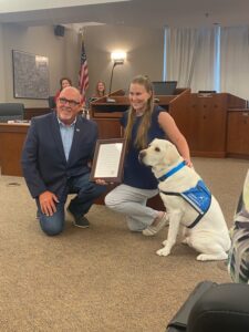 Woman with a service dog and a man holding a proclamation in Rochelle IL