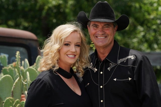 Woman standing next to a man in cowboy attire