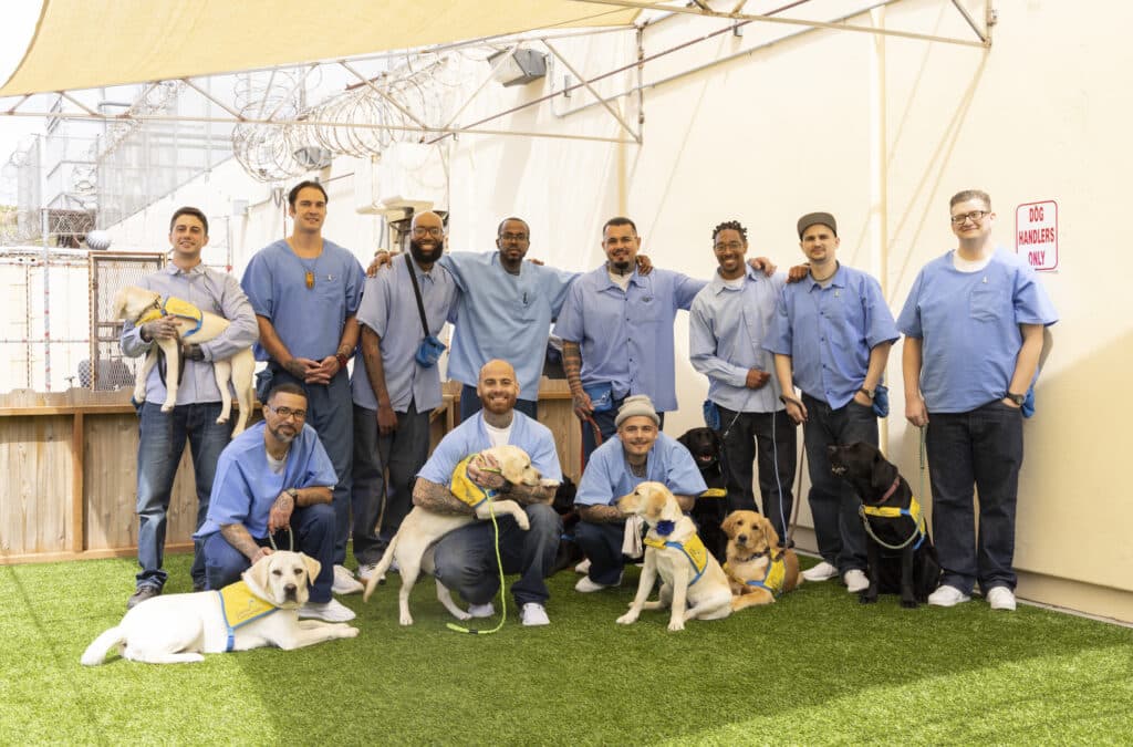 Eleven puppy raisers at San Quentin Rehabilitation Center pose with their Canine Companions puppies.
