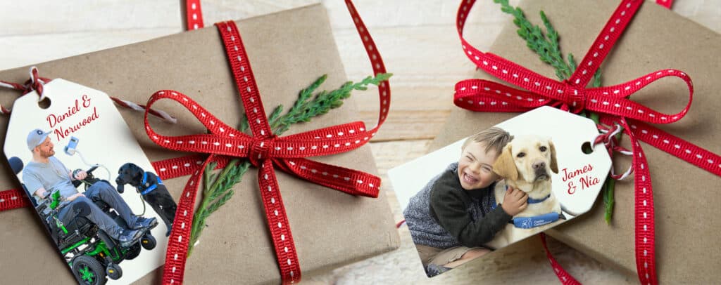 Two wrapped gifts with red striped ribbons and gift tags featuring individuals with service dogs.