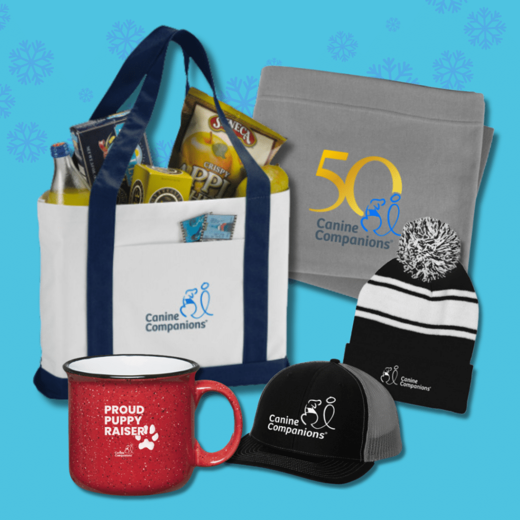 Merchandise items including a tote bag with snacks, a gray fleece blanket with "50 Canine Companions" logo, a pom-pom beanie, a black cap, and a red mug labeled "Proud Puppy Raiser."