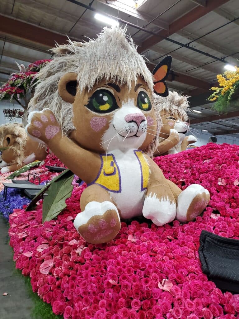 A fake lion cub waves from the top of a parade float for the 136th annual Rose Parade, featuring Lions Club and Canine Companions.