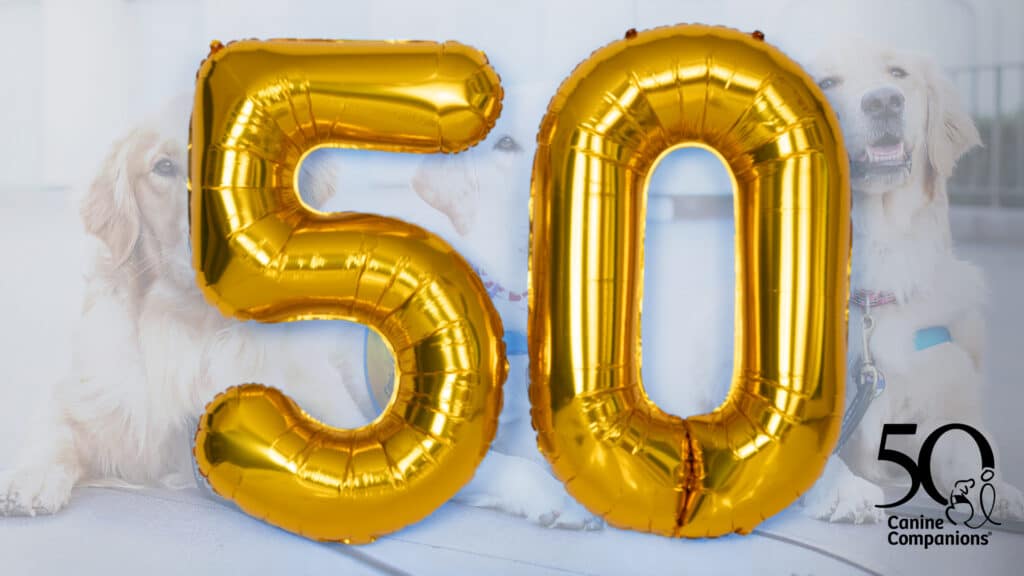 Large golden balloons in the shape of the number 50, with images of dogs and the Canine Companions logo in the background, signifying a celebration or anniversary.