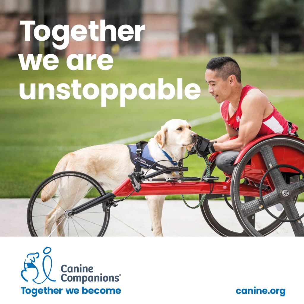 A man in a red tank top, seated in a red wheelchair, smiles at a yellow Labrador retriever wearing a harness. They are in a grassy area, highlighting the bond between humans and service dogs, accompanied by the text 'Together we are unstoppable.'