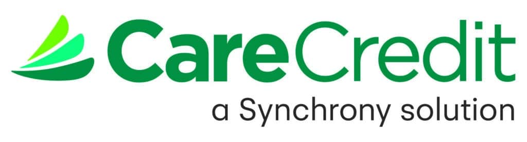 Logo of CareCredit, featuring green text for 'CareCredit' and a graphic element with stylized green shapes, followed by the tagline 'a Synchrony solution' in black text.