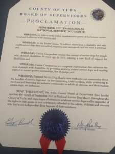 A proclamation from the County of Yuba Board of Supervisors honoring September 2025 as National Service Dog Month, highlighting the importance of service dogs for individuals with disabilities and encouraging community support and awareness. The document features a blue seal and is signed by the Chairman and Clerk of the Board.