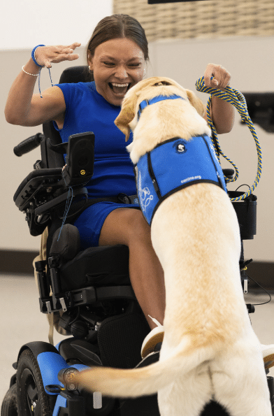 young woman in wheel chair smiling at her service dog