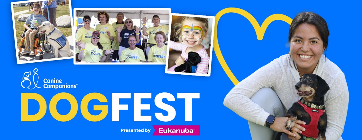 Smiling woman kneeling and holding a black dog in a red harness beside a bright blue DogFest banner with montage photos and yellow heart.
