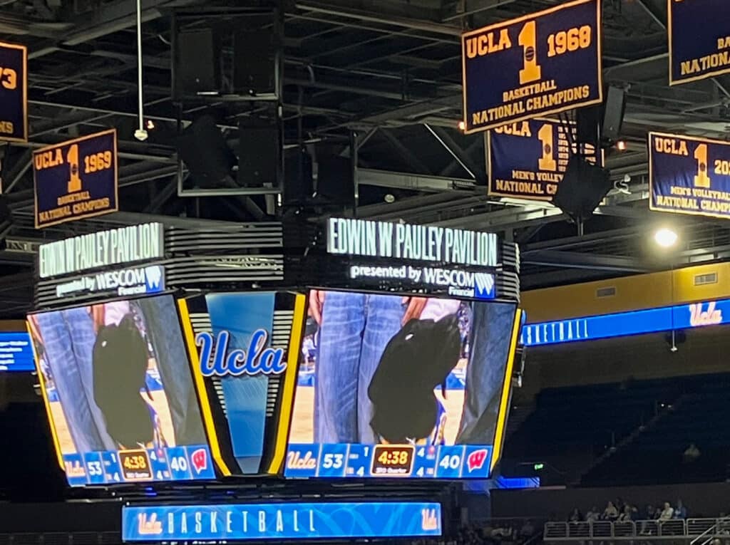 Jumbotron at Edwin W. Pauley Pavilion showing UCLA logo, score 53–40, and hanging national-championship banners.