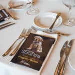 Canine Companions program guide on a formal table setting with silverware, plates, and wine glasses
