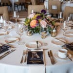 Elegant banquet table set with floral centerpiece, wine glasses, menus, and a Canine Companions program guide