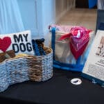 Auction display of dog-themed gift baskets, including a "My Dog" pillow and a sign for "I Love Dogs!
