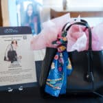 Auction display featuring a black Jimmy Choo tote with a colorful silk scarf and pink tissue paper