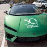 Green Lamborghini sports car with Canine Companions 50th anniversary logo on the hood, parked outdoors