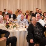 Guests seated at banquet tables listening at an event