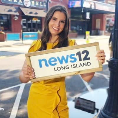 woman holding a news 12 long island sign