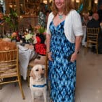 Woman standing with a service dog in a blue Canine Companions vest at a formal indoor event