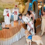 Canine Companions service dog in blue vest with a woman at a formal event auction table