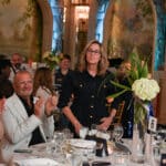 Guests applaud a woman standing at a banquet table during a formal Canine Companions event