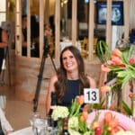 Guests seated at a floral banquet table during an event, smiling and chatting
