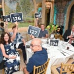 Guests at a charity dinner hold up auction paddles around a decorated table